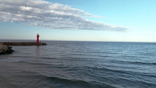 Calm Sea with a Red Lighthouse at Dusk