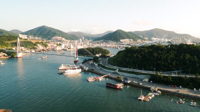 Coastal City with Bridge and Boats at Sunset