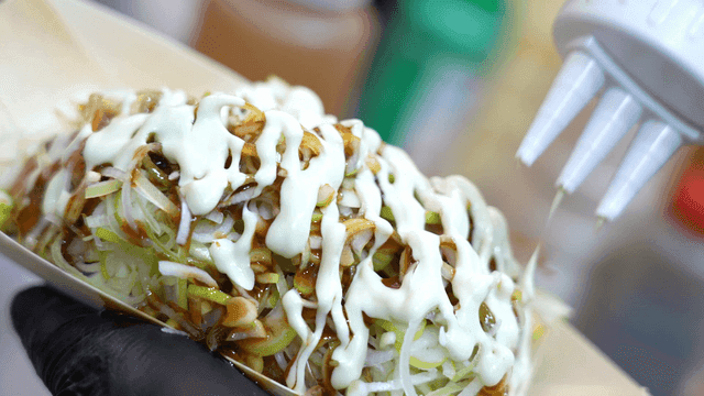 Mayonnaise poured over takoyaki topped with plenty of green onions