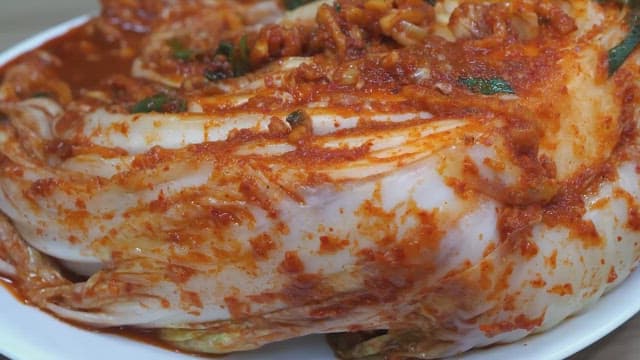 비닐 장갑을 끼고 전통 김치를 들어올리는 사람