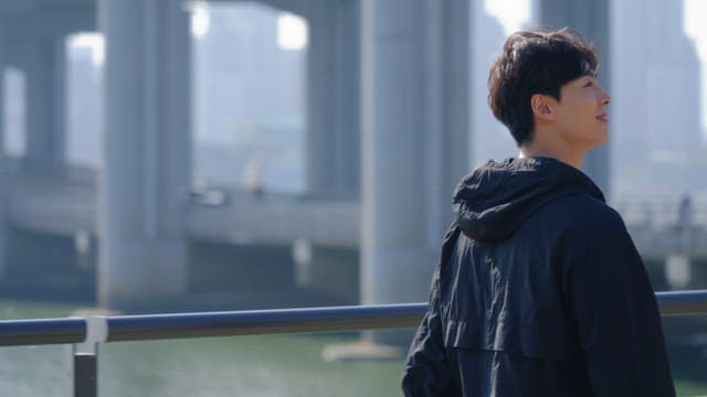 Man walking under a bridge by the river