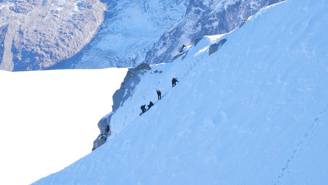 Climbers ascending a snowy mountain slope