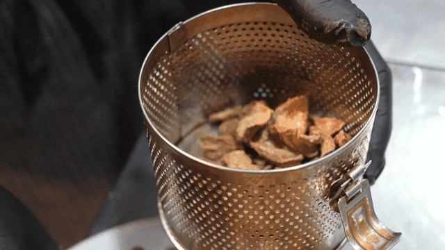 Chef who puts dried medicinal herbs into metal sieve