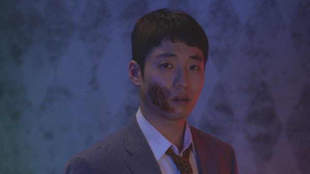 큰 흉터가 있는 얼굴의 남자가 투덜더리는 장면