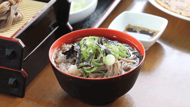 A bowl of soba noodles with garnish