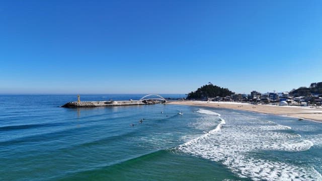 Beach with surfers and a pier