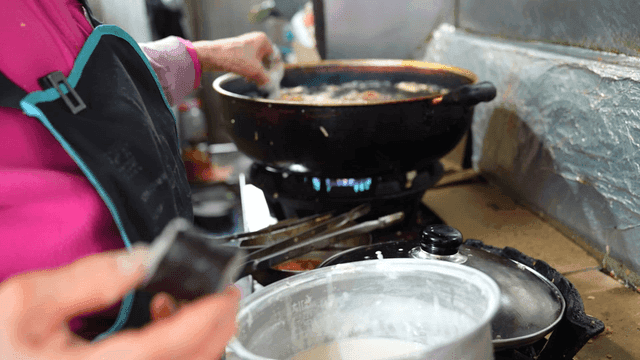 Person coating and frying seaweed rolls in kitchen