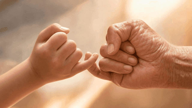 Child's little finger holding adult's finger