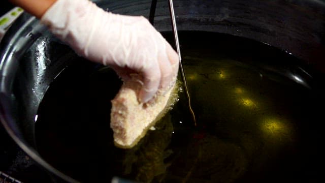 Breaded raw pork being fried in hot oil