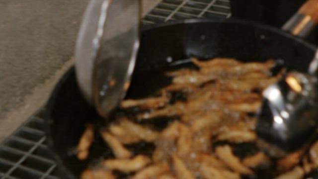 Deep frying battered fish in hot oil using a ladle