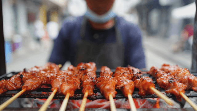 Street vendor grilling muping skewers