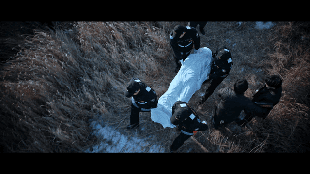 Rescue team carrying a covered body in a field