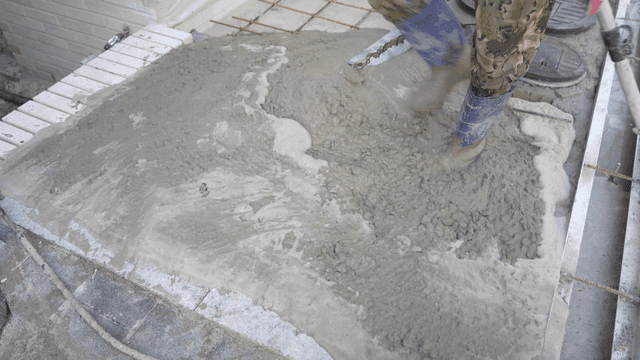 Worker smoothing wet concrete with a tool