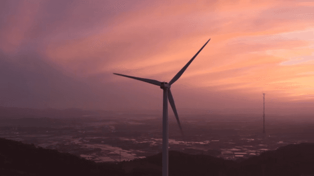 핑크빛으로 물들은 하늘 아래 산악 지역의 풍력 터빈