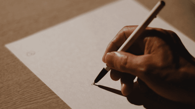 Person writing on paper with focus