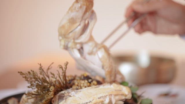 삼계탕에서 큰 닭다리를 집어 그릇에 담는 모습