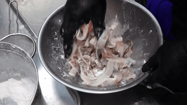 금속 그릇에서 오징어와 밀가루를 섞는 모습