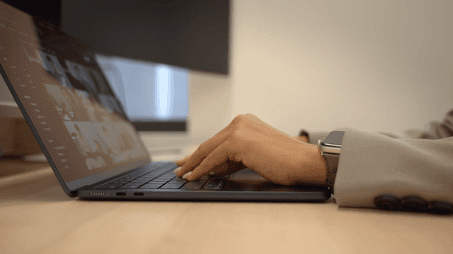 Hands typing on laptop in office