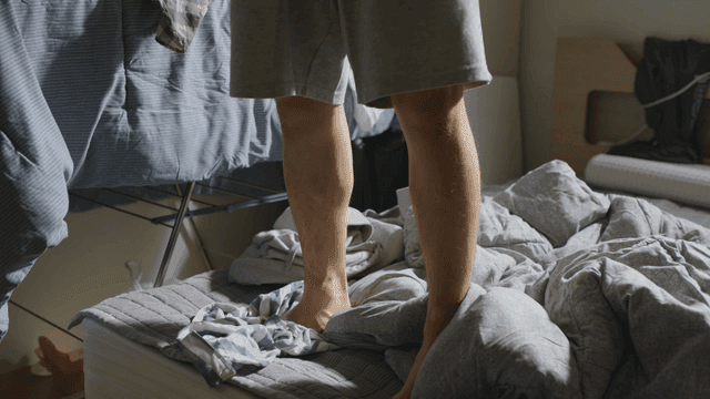Person standing on a messy bed in the morning