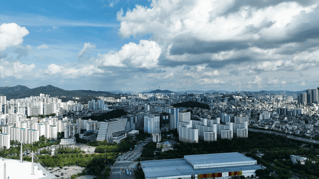 Panoramic view of city spread out under cloudy sky.