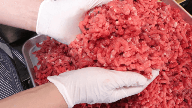 장갑을 낀 손이 다진 고기를 다루는 모습