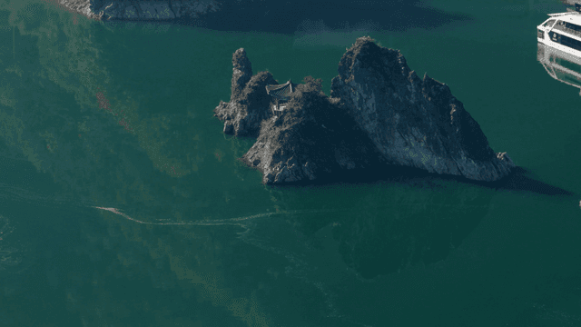 바위 섬과 배가 있는 고요한 호수