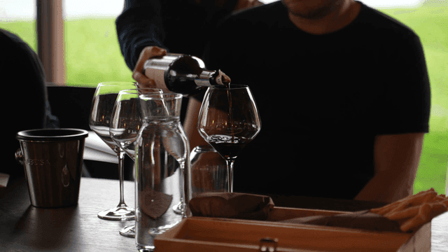Waiter pouring red wine into wine glass