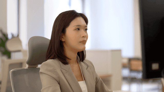 Female office worker drinking coffee in paper cup while working in office