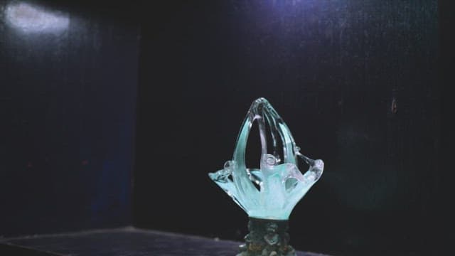 어두운 방에서 정교한 유리 공예품을 살펴보는 남자