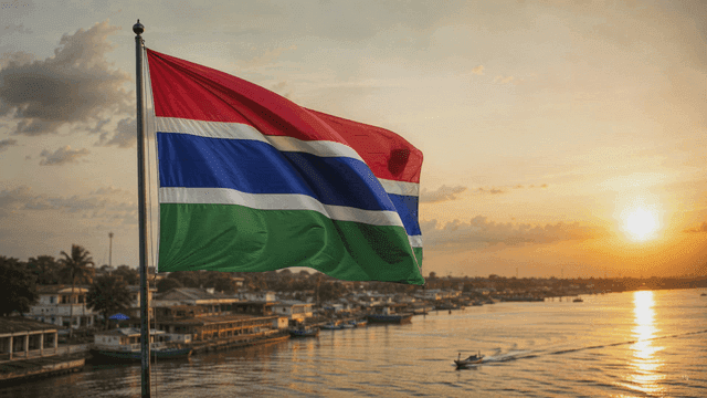 Gambian flag fluttering at sunset by river