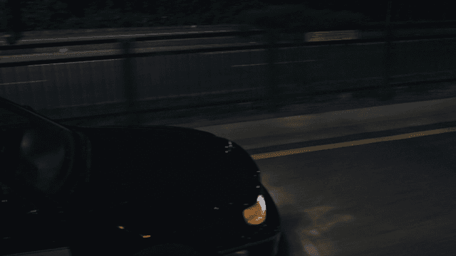A black car driving on a road at night