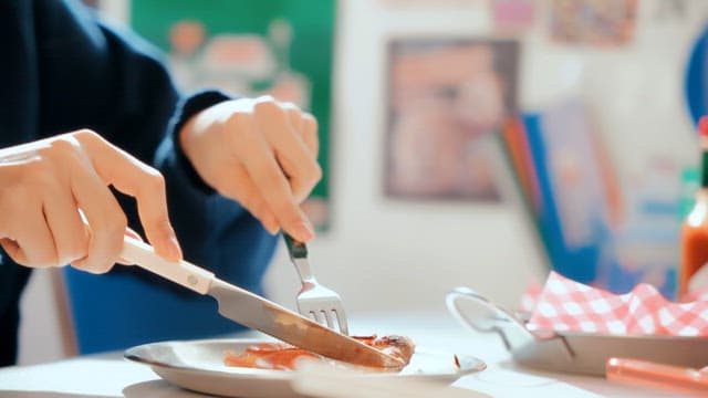 Person cutting pizza to eat indoors