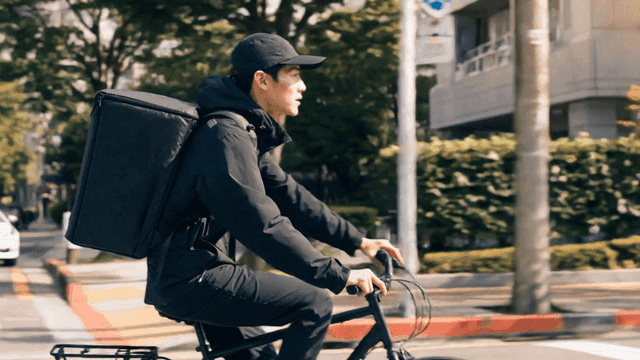 도로를 자전거로 달리는 배달원