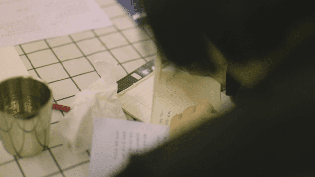 Back view of person drawing on letter at table