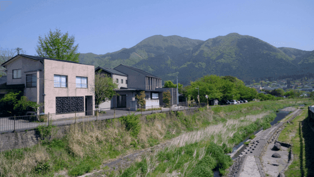 Houses by a river with mountains in the background