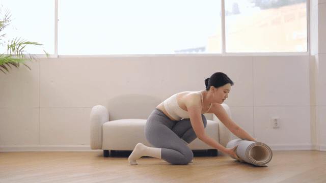 실내에서 매트를 정리하는 여성