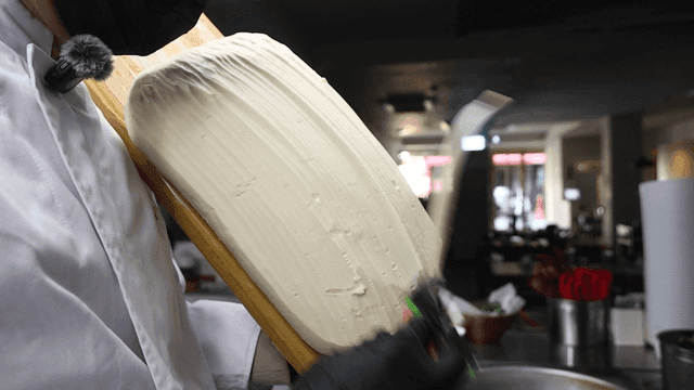 Chef cooking hand-cut noodles in kitchen