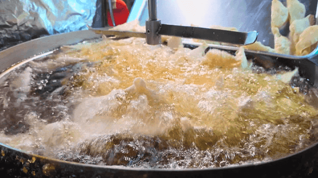 뜨거운 대형 튀김기 기름에 튀겨지는 만두