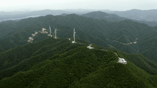 Wind turbines above lush mountainous terrain