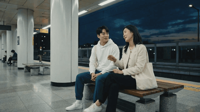 Couple sitting on bench at subway station at night
