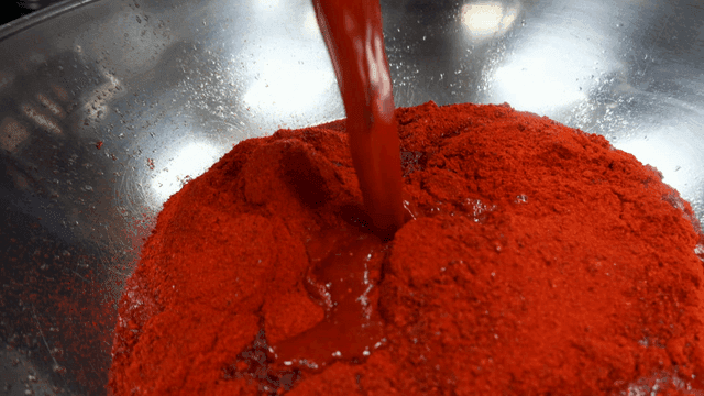 Mixing red sauce and chili powder in bowl