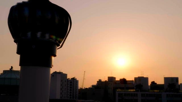 Sunset over city buildings with a ventilator