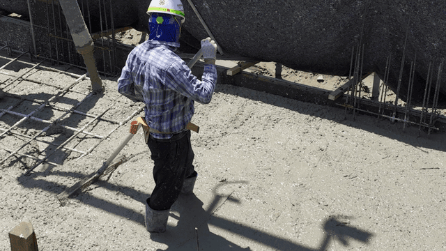 Worker smoothing concrete at a construction site