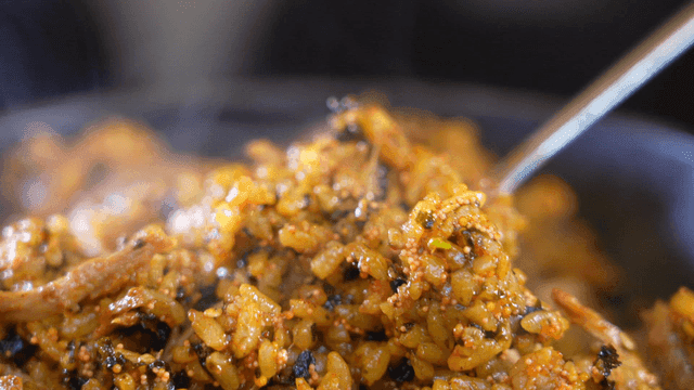 Spoon scooping hot fried rice from pan