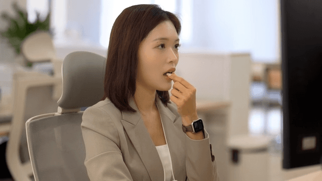 Female office worker taking medicine in office