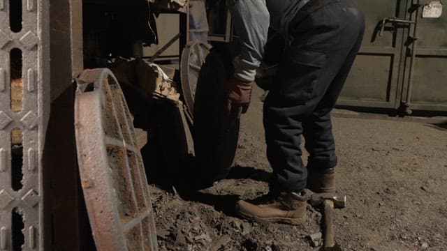 Worker handling metal parts in a factory