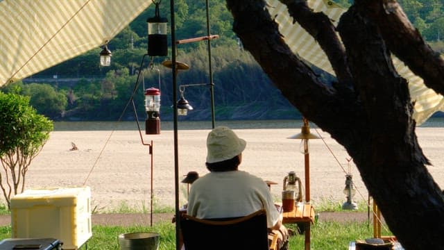 Resting under a tent on the riverside decorated with camping equipments