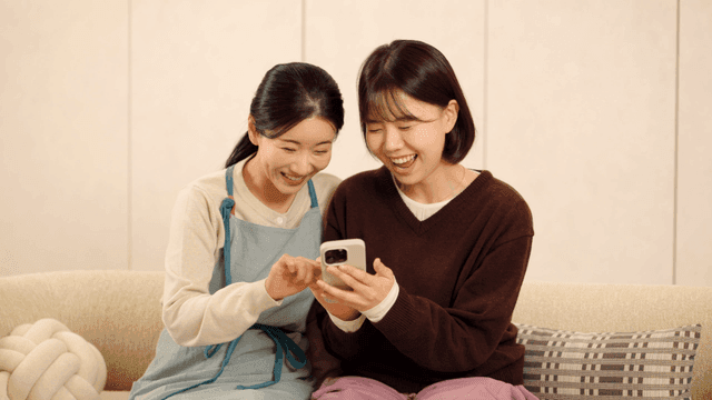 Mother and daughter looking at their smartphones together
