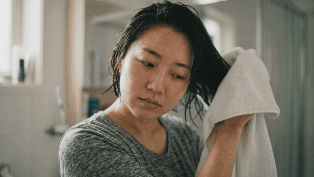 Woman drying her hair with towel.
