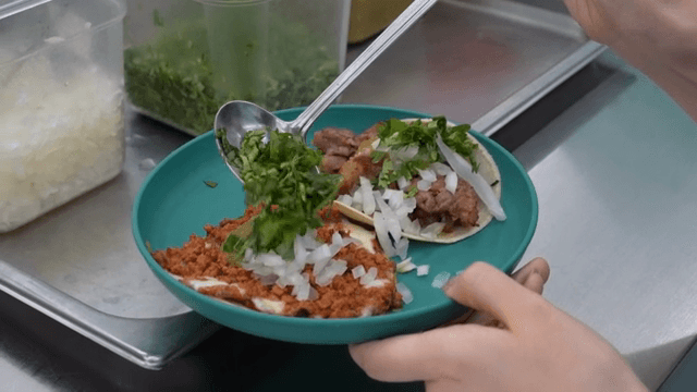 Tacos being garnished with fresh cilantro